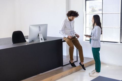 Diverse coworkers collaborating at office reception desk