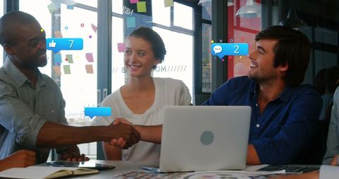 Diverse Coworkers Shaking Hands in Office Surrounded by Social Media Icons