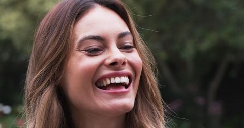 Cheerful Woman Laughing in Lush Garden