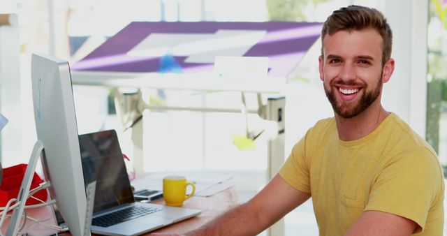 Young professional smiling while working in bright office setting - Download Free Stock Images Pikwizard.com