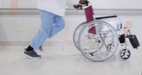 Nurse pushing wheelchair down hospital corridor with motion blur conveying urgency