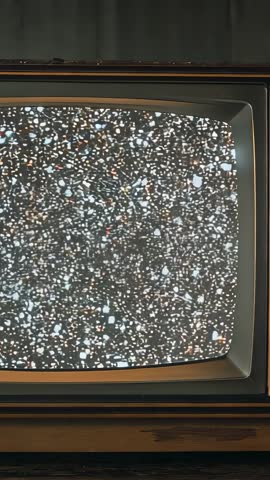 Vertical zoom revealing vintage CRT TV static on retro wooden cabinet, nostalgic analog noise