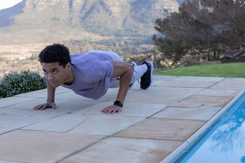 Man Performing Push-ups Outdoors Near Pool in Fitness Attire