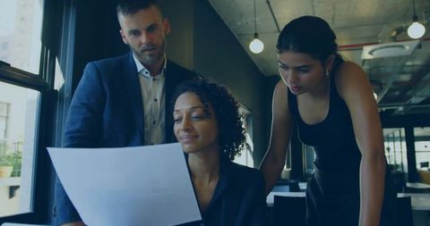 Multicultural team reviewing report in modern open-plan office for strategic planning