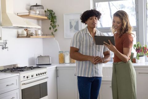 Young couple using tablet for cooking plans in bright modern kitchen