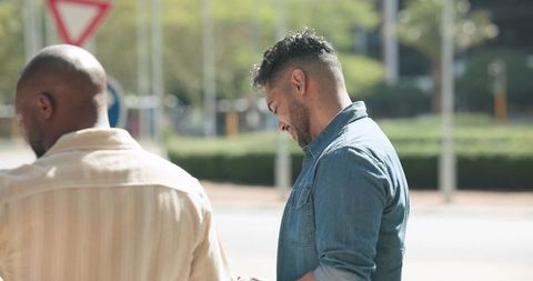 African american men checking smartphone on urban sidewalk, casual friends in daylight