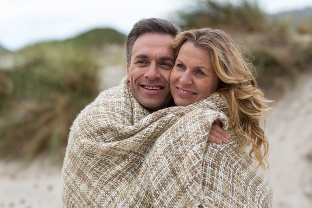 Romantic Mature Couple Wrapped in Blanket on the Beach - Download Free Stock Photos Pikwizard.com