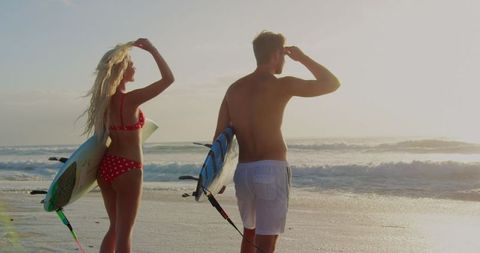 Couple Standing with Surfbords on Sunlit Beach