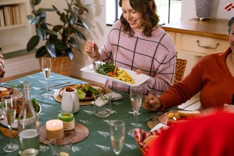 Family Gathering with Holiday Meal Passing Vegetables Around Table