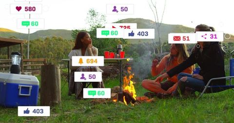 Friends gathering around campfire with social media overlay at rustic campsite, outdoor lifestyle