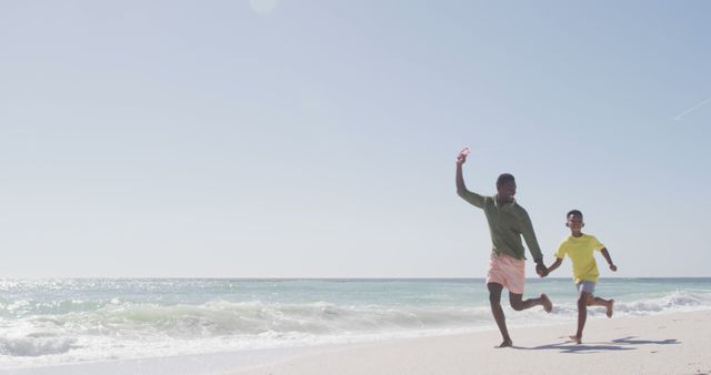 Father and son joyfully running on sandy beach by ocean - Download Free Stock Images Pikwizard.com