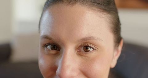 Woman holding neutral expression with brown eyes and natural skin in cozy living room