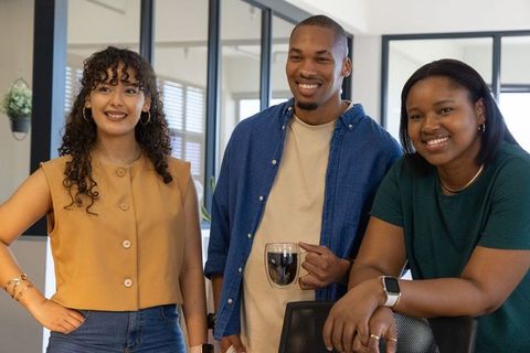 Diverse coworkers smiling and collaborating in modern sunlit office during casual meeting