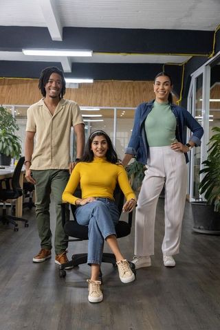 Young diverse team collaborating in open-plan office with woman in mustard turtleneck