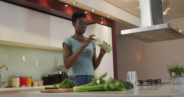 Smiling african american attractive woman tasting homemade smoothie in kitchen. healthy nutrition and lifestyle at home.