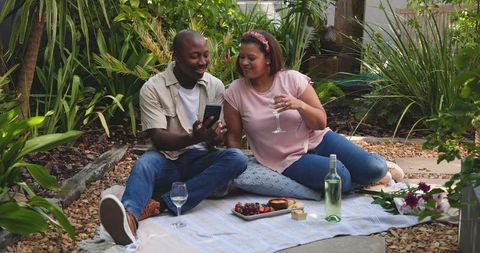Romantic Couple Enjoying Picnic with Wine and Smartphone Outdoors