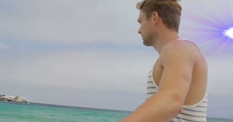 Man with bicycle on beach under bright light beam