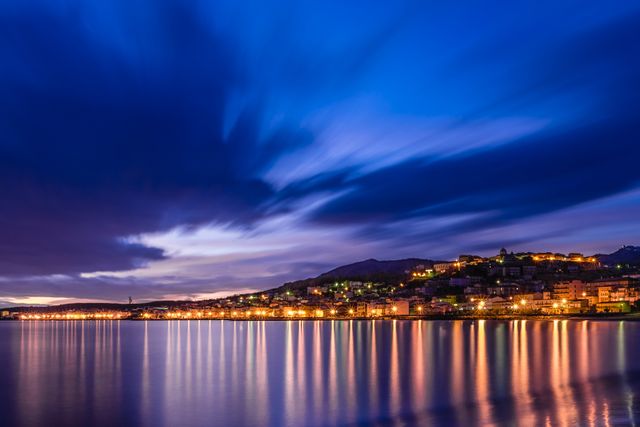 Blue hour over illuminated coastal town with reflections on water - Download Free Stock Photos Pikwizard.com