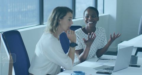 Diverse Female Colleagues Collaborating at Office Desk with Laptop