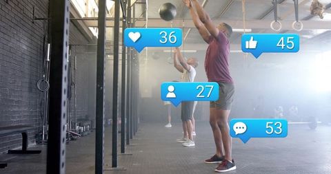 Athletic Men Practicing Medicine Ball Workout in CrossFit Gym