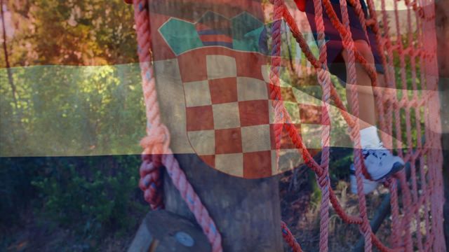 In the video, a young biracial boy is shown training on an obstacle course. He is climbing a rope structure with a Croatian flag superimposed on the scene, symbolizing national pride and the importance of sports. This video can be used for campaigns promoting national identity, physical fitness, youth sports, and multicultural engagement. Ideal for use in advertisements, educational materials, and promotional content.