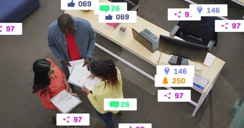 Overhead view of coworkers collaborating and reviewing documents with social notifications