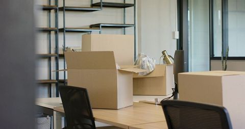 Office relocation with open cardboard boxes on desks, bubble wrap and empty shelves