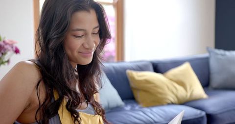 Smiling Teen Sitting at Home Reading Book on Couch