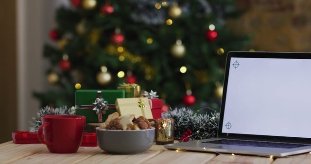 Image of wooden table with christmas decorations and laptop with blank screen over christmas tree. christmas, communication, tradition and celebration concept.
