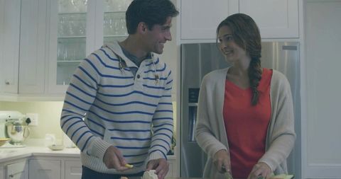 Couple chopping vegetables and sharing smiles at modern kitchen island