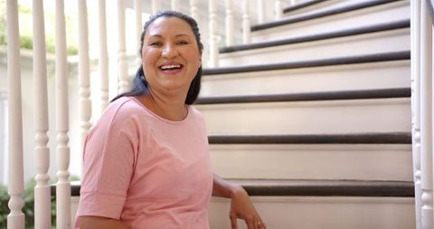 Happy mature woman relaxing on staircase in comfortable home