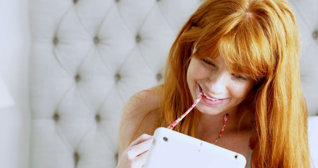 Red Haired Woman Chewing Glasses and Using Tablet in Bed - Download Free Stock Images Pikwizard.com