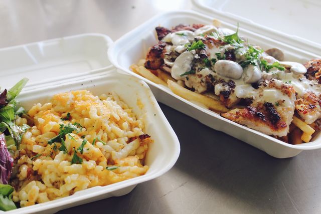 Grilled chicken with mushroom cream sauce served with French fries, and cheesy pasta with side salad, prepared and artfully arranged in takeout containers. Perfect for promoting food delivery services, gourmet food offerings, caterers, and high-quality restaurant meals.
