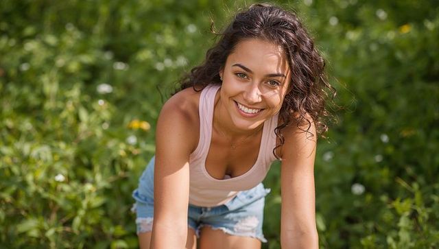 Joyful Woman Enjoying Outdoors in Sunny Meadow with Warm Smile