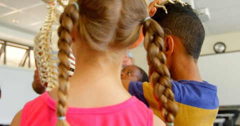 Curious Schoolchildren Studying Human Skeleton Model in Classroom