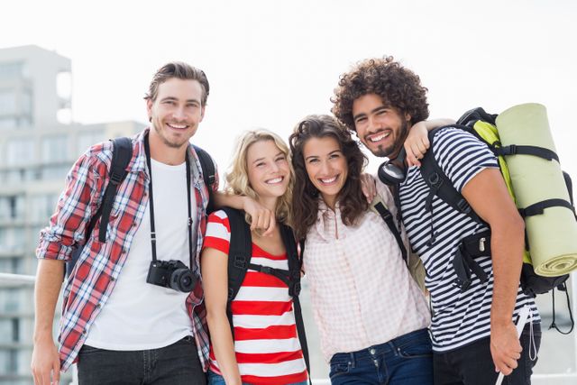 Group of friends standing close together with arms around each other, smiling and wearing casual clothes with backpacks. Ideal for use in travel blogs, friendship-themed content, advertisements for outdoor gear, and social media posts promoting adventure and camaraderie.