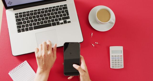 Hands using laptop and smartphone, with coffee and calculator on red desk. Business, communication, and remote working concept digitally generated image.