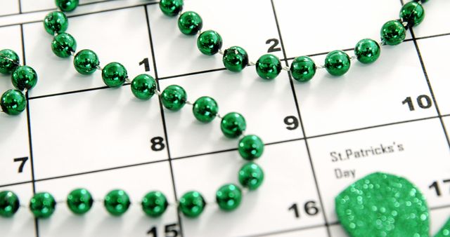 This image displays green beads positioned on a calendar, with focus on the date March 17 marked as St. Patrick's Day. Ideal for promoting St. Patrick's Day events, Irish culture, holiday decorations, party planning, and celebratory traditions.