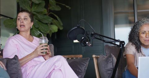 Mature women recording casual podcast conversation in cozy living-room style studio