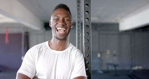 Joyful athlete standing in modern gym, boosted fitness inspiration