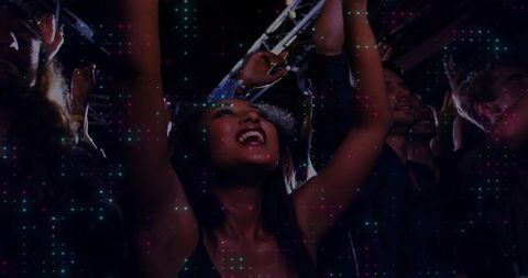 Young diverse crowd dancing and cheering under neon led lights in energetic nightclub