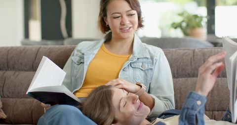 Multicultural couple reading together on sofa, cozy home relaxing and intimate moment