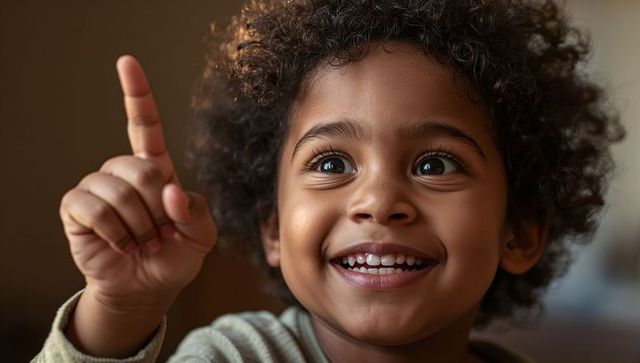 Joyful preschool child smiling and pointing upward with curly hair and toothy grin in warm light