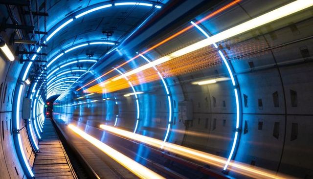 Futuristic metro tunnel with blue led rings and high-speed train light trails long exposure
