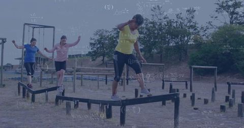 Fitness enthusiasts balancing on outdoor obstacle course beam