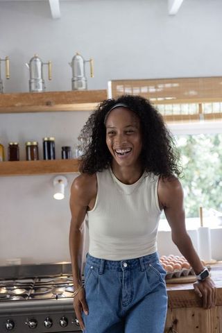 Smiling african american woman leaning on rustic kitchen counter with egg tray, morning