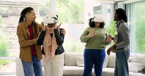 Diverse couples experiencing virtual reality at home with VR headsets in living room