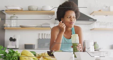 Tasting green smoothie while preparing healthy breakfast in modern kitchen with blender