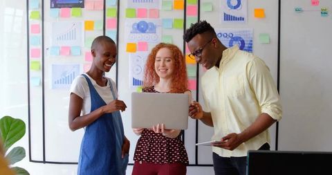 Collaborative Team Analyzing Data on Laptop and Tablet in Office