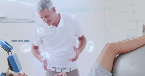 Physiotherapist assessing leg rehabilitation using exercise ball while guiding patient